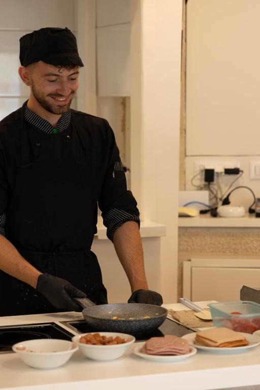 a man standing in a kitchen preparing food at Eva Mare Hotel & Suites - Adults only in Agia Pelagia