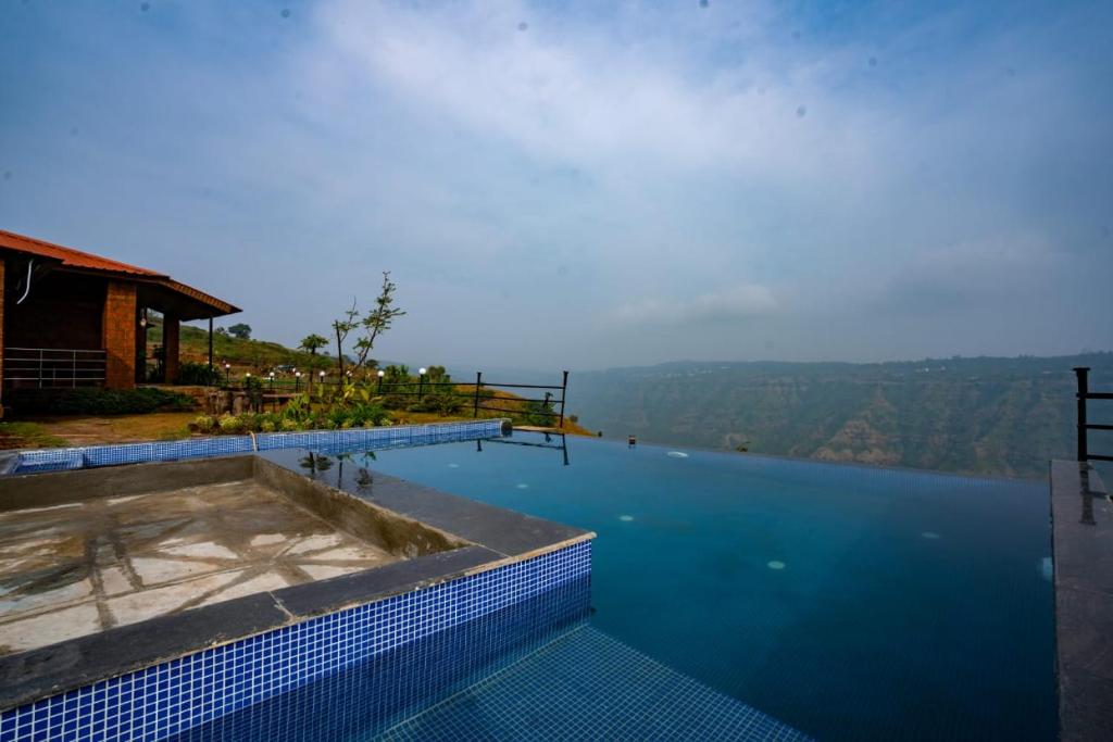 einen Pool mit Blick auf das Wasser in der Unterkunft Lifeline Villas - Miracle Villa 5bhk Valley View in Mahabaleshwar