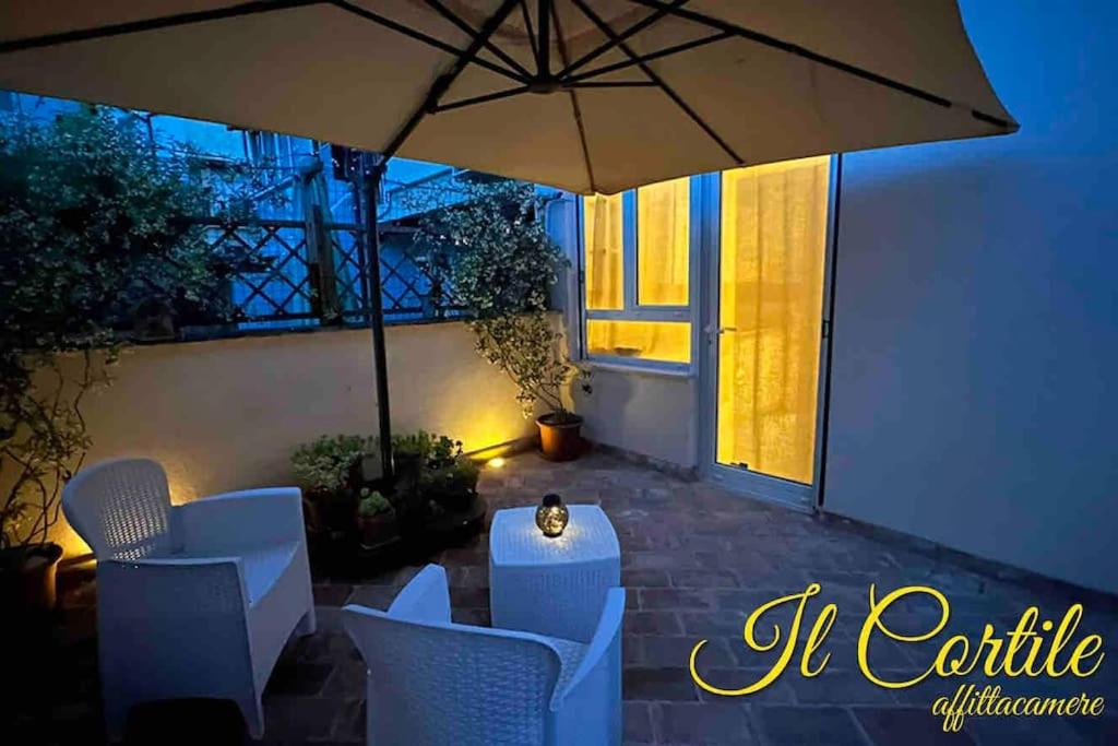 eine Terrasse mit einem Tisch, Stühlen und einem Sonnenschirm in der Unterkunft Affittacamere Il Cortile in Chiaravalle