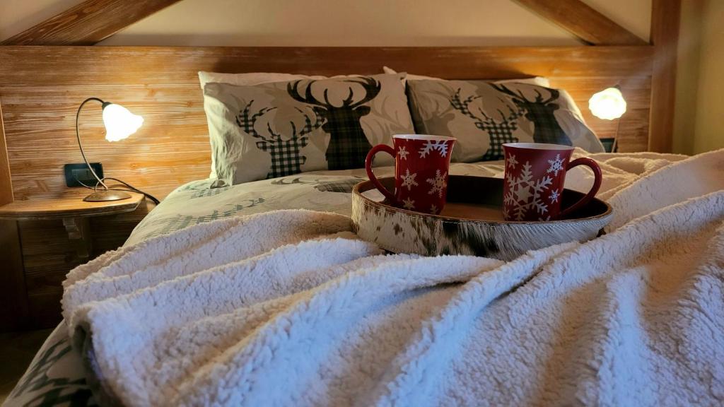 a bed with two mugs on a tray on it at Baita 3 lovely & central Sauze in Sauze dʼOulx