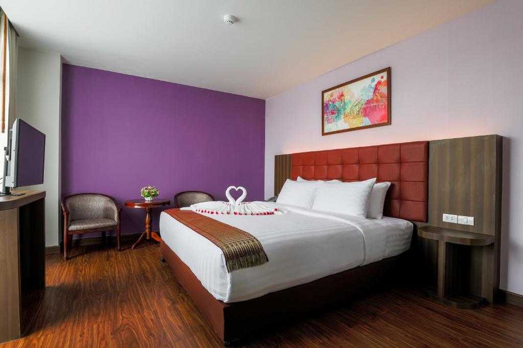 Cette chambre d'hôtel dispose d'un grand lit et de murs violets. dans l'établissement Grandpink park hotel, à Hat Yai