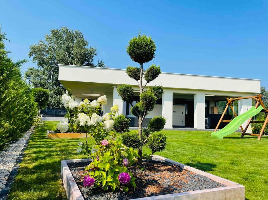 Győrzámoly的住宿－Tóparti Villa, Jakuzzi,Luxus élmény a Szigetközben，一个带游乐场的花园的房子