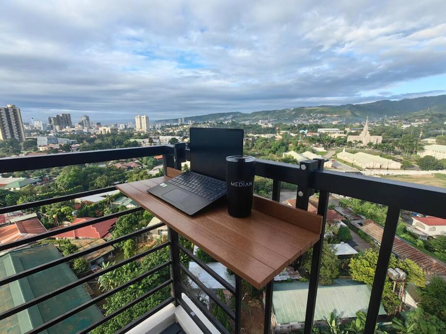 宿霧市的住宿－Studio Unit with Balcony at the Median，阳台上的一张木桌旁的笔记本电脑