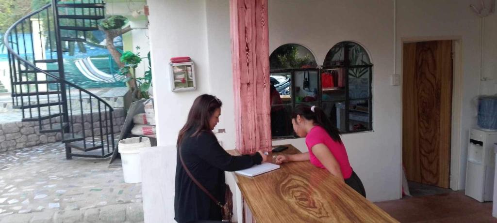 Deux femmes se tenant à un comptoir en agitant la main dans l'établissement Bungalow in Holidays Beach Resort, à Bolinao