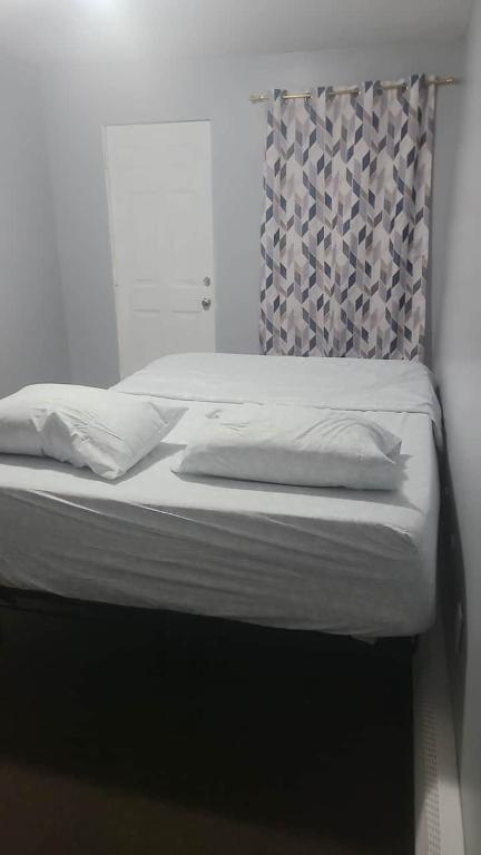 a bed with white sheets and a headboard in a bedroom at Room in a Beach House with Queen bed in a landlord hosted three bedroom apartment in Edgemere