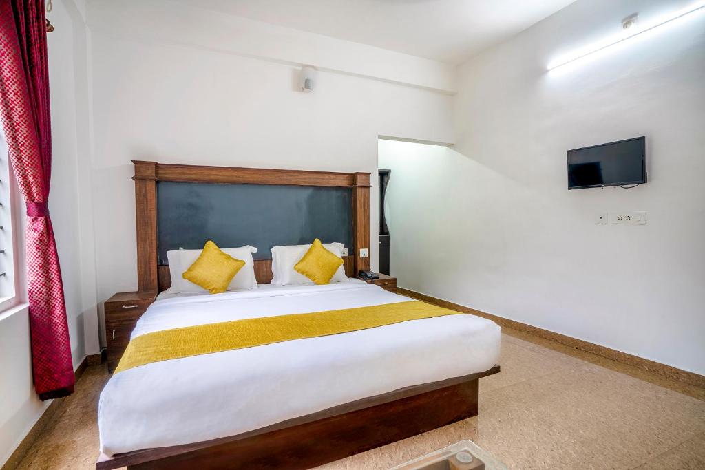 1 dormitorio con 1 cama grande con almohadas amarillas en FabHotel Abrigo Residency en Munnar