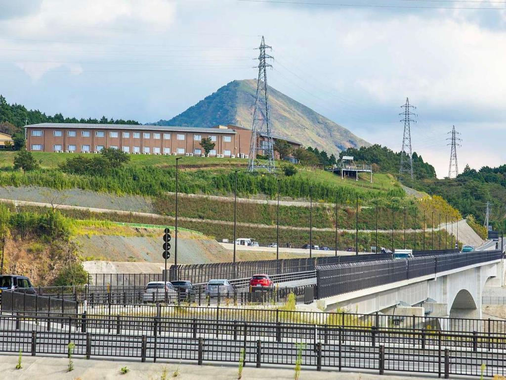 a bridge over a highway with a mountain in the background at Aso Canyon Terrace & Lodge in Minami Aso