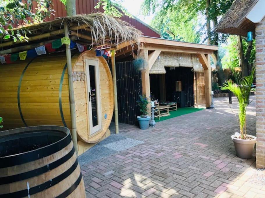 a house with a patio with a building at Zentopia: vakantiehuis met wellness en meer. in Hulshorst