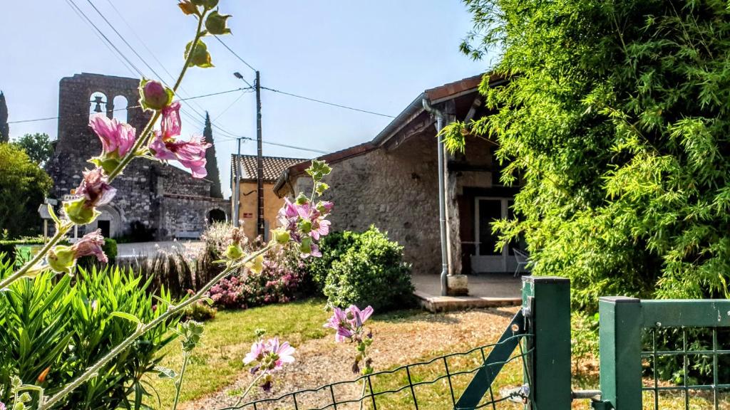 una casa con una valla y flores delante de ella en Cottage - Idéal pour 2 - Terrasse - Jardin - Piscine - 25 minutes d'Agen - SPA en option, en Bourran