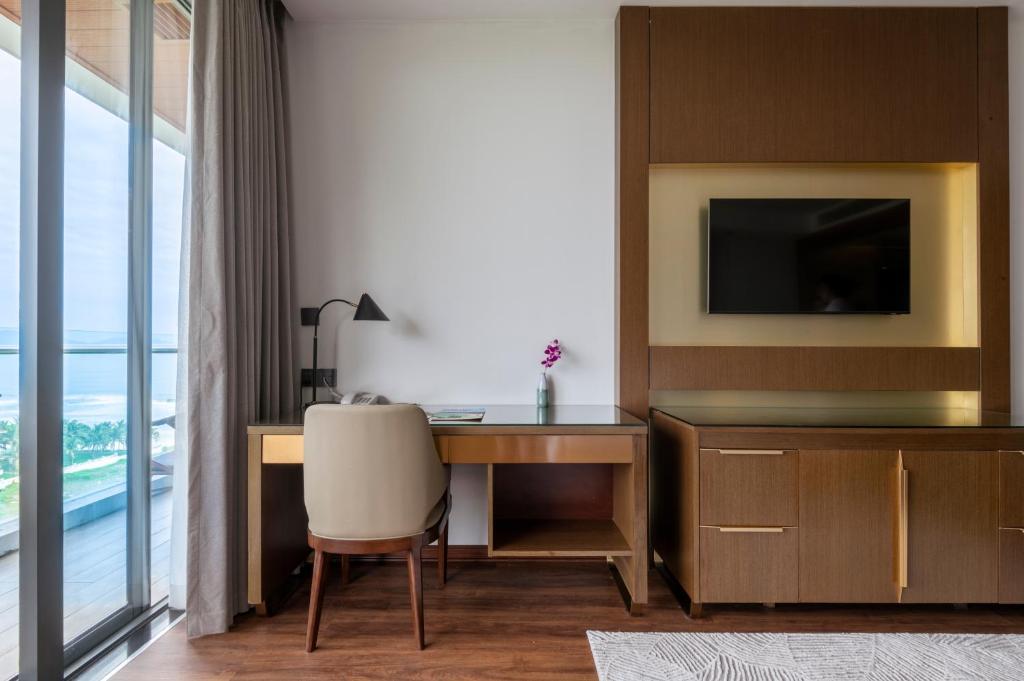 A compact built-in desk beside a window, with a television and glimpse of water beyond.