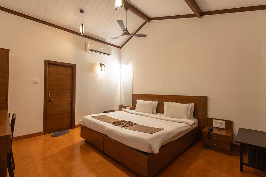 a bedroom with a large bed with a ceiling fan at Scarlet Resort in Matheran