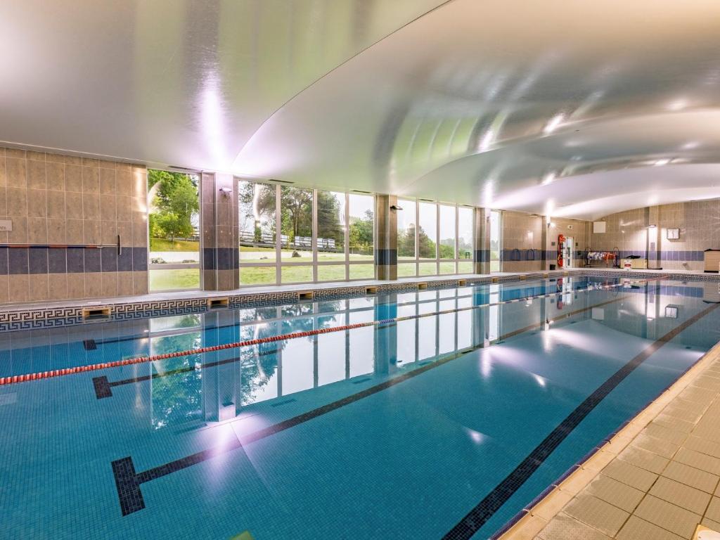 a large indoor swimming pool with blue water at 2 Bed in St. Mellion 87704 in St Mellion