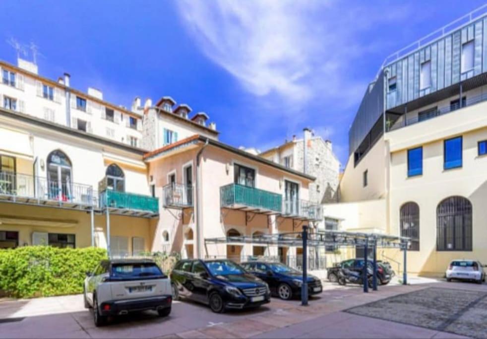 un parking avec des voitures garées devant les bâtiments dans l'établissement Magnifique Duplex Type Loft, à Nice