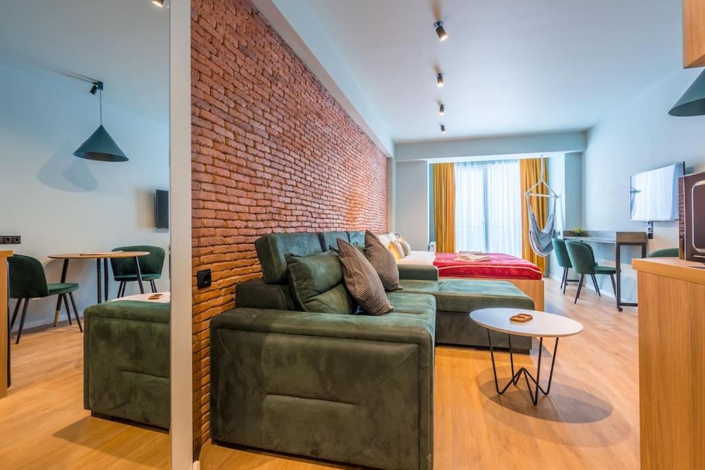 sala de estar con sofá y pared de ladrillo en New Gudauri Cozy Apartment with a Mountain View, en Gudauri