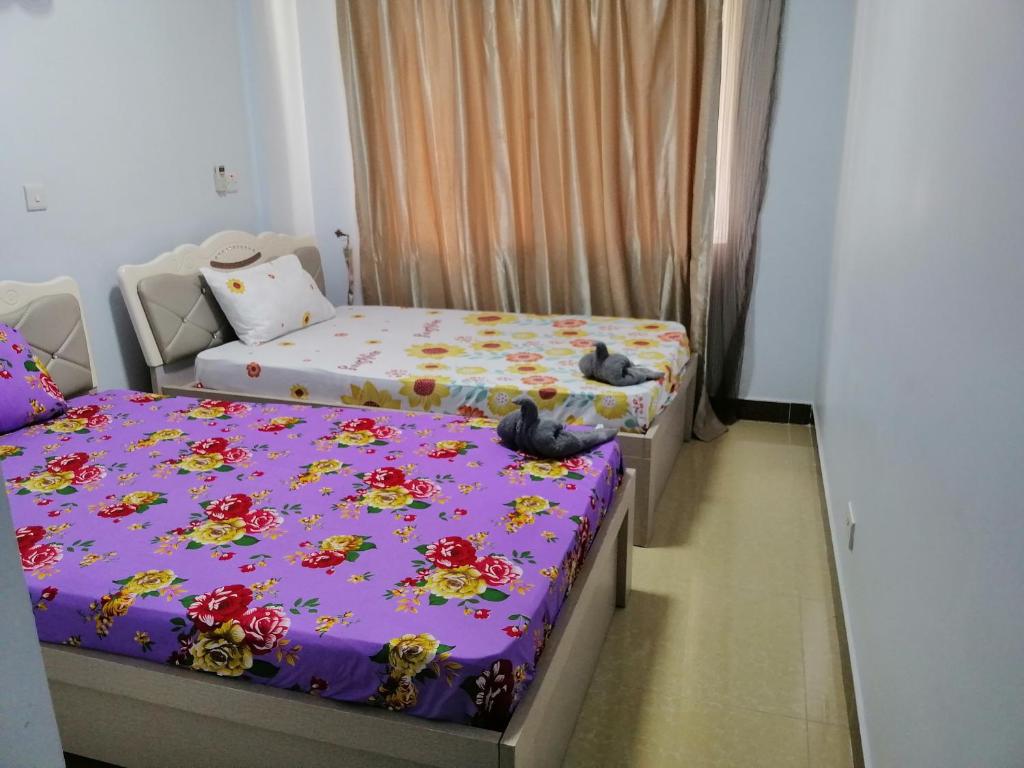 two beds in a small room with purple sheets at Mariana Shared Home in Dar es Salaam