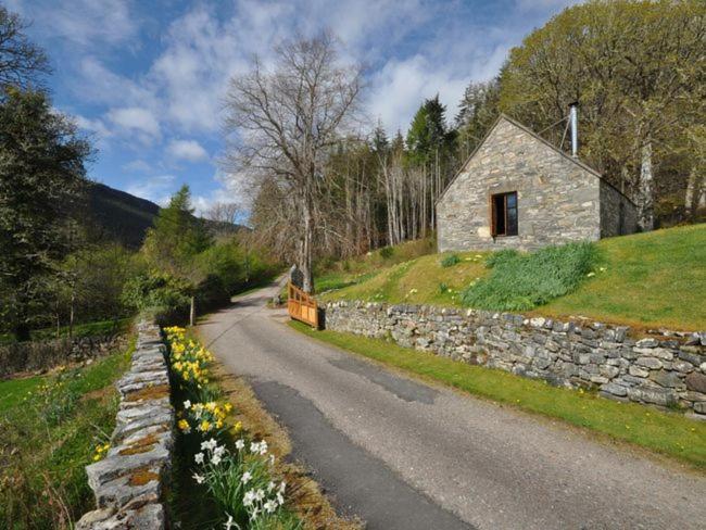 una carretera que conduce a un edificio de piedra en una colina en 1 Bed in Loch Ness I662C, en Invermoriston