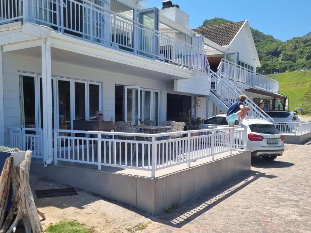 a woman standing on the balcony of a house at Beachfront property, Victoria Bay, Garden route in Victoria Bay