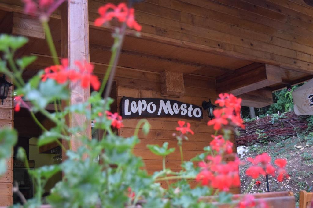 un cartello sul lato di un edificio con fiori rossi di Motel Lepo Mesto a Strmosten