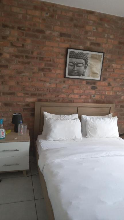 a bedroom with two white beds and a brick wall at Euphoria in Nelspruit