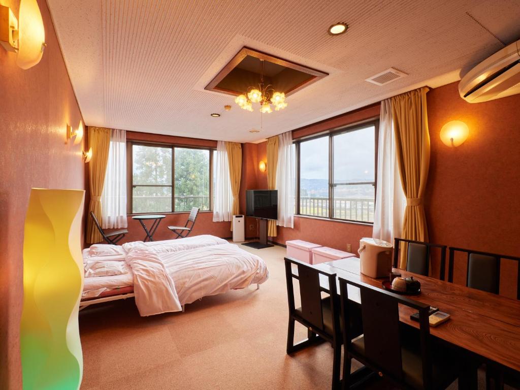 a bedroom with a bed and a desk and windows at Hayamasou in Tokamachi