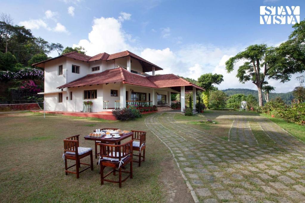 a table and chairs in front of a house at 3BR Mercara Hill Homestay with Outdoor Jacuzzi and Comp breakfast - Madikeri in Madikeri