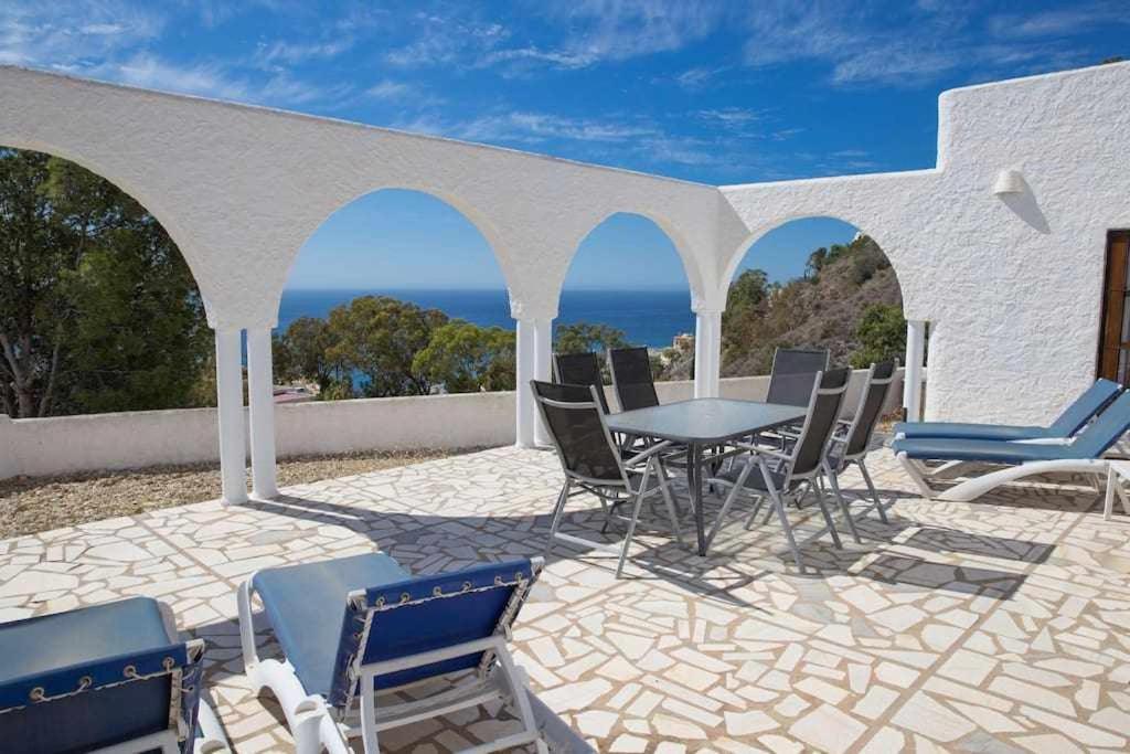 un patio con mesa, sillas y el océano en Casa de montaña de 3 dormitorios con vistas al mar, en Mojácar