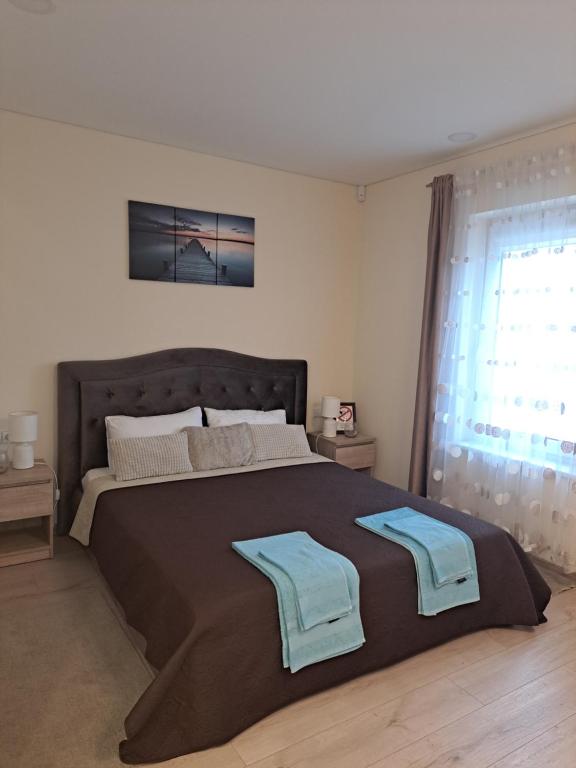 a bedroom with a large bed with two towels on it at LIUX apartamentai in Kaunas