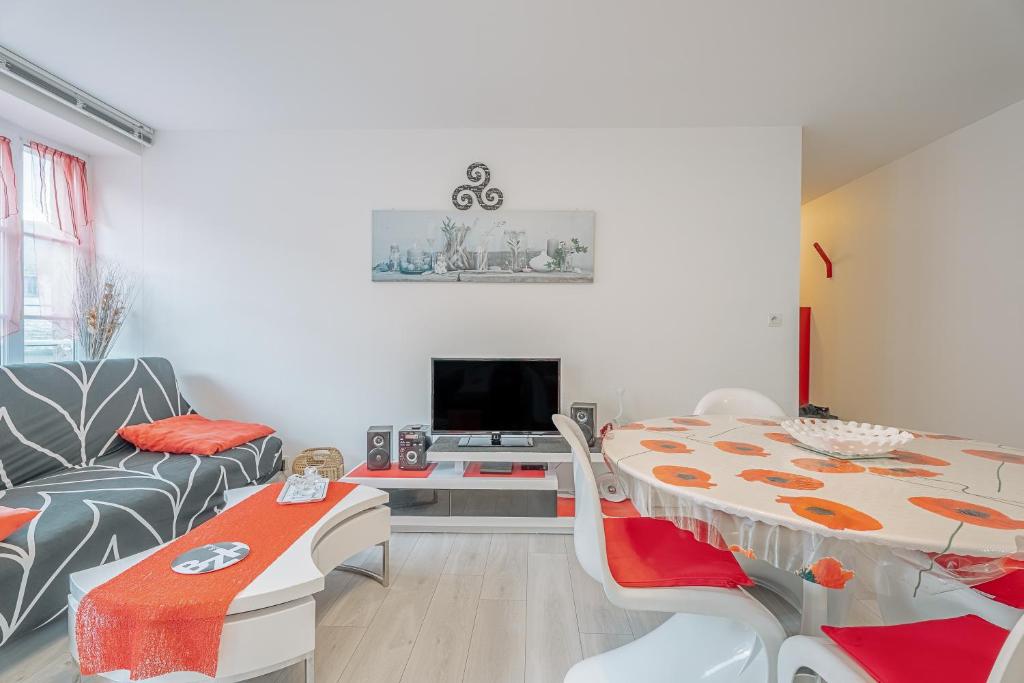 a living room with a table and a tv at Appartement Les Bains - Erquy in Erquy