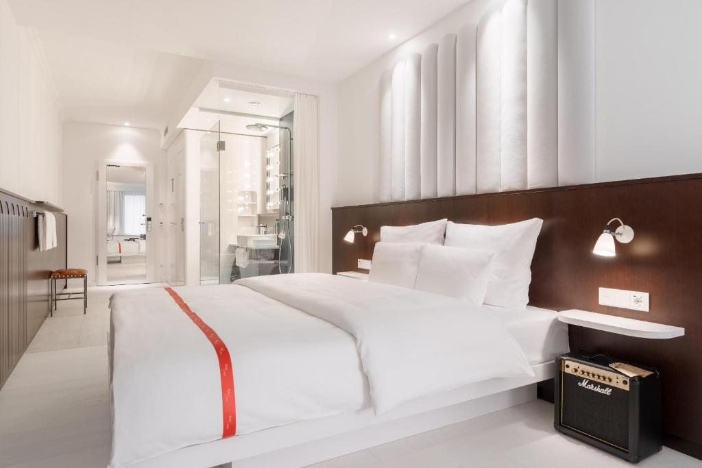 a bedroom with a large white bed with a wooden headboard at Ruby Hanna Hotel Stuttgart in Stuttgart