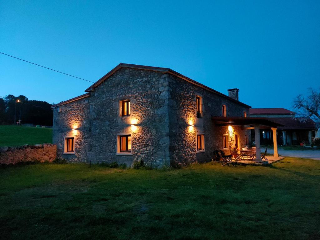 a stone house with lights on the side of it at O Rincón de Esther in Vedra