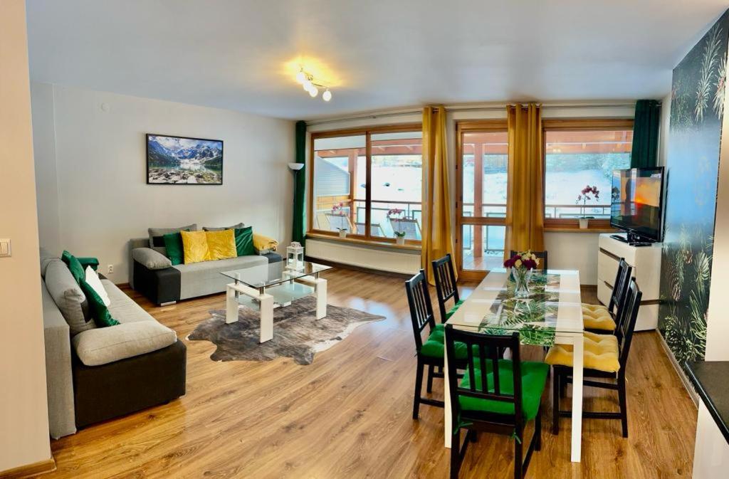 een woonkamer met een tafel en een bank bij Apartament Morskie Oko ApartamentyZakopianskie Basen Sauna Jacuzzi in Zakopane