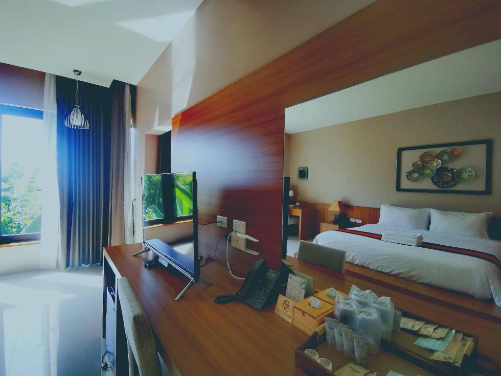 Bangnu Greenery Resort في Takua Thung: غرفة نوم بسرير ومكتب مع تلفزيون