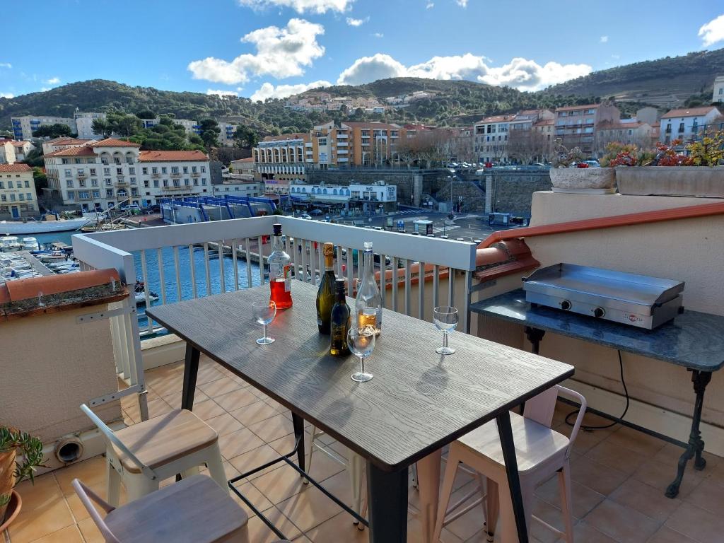 une table avec des bouteilles de vin et des verres sur un balcon dans l'établissement La Terrasse du Vénus - Port Vendres, à Port-Vendres