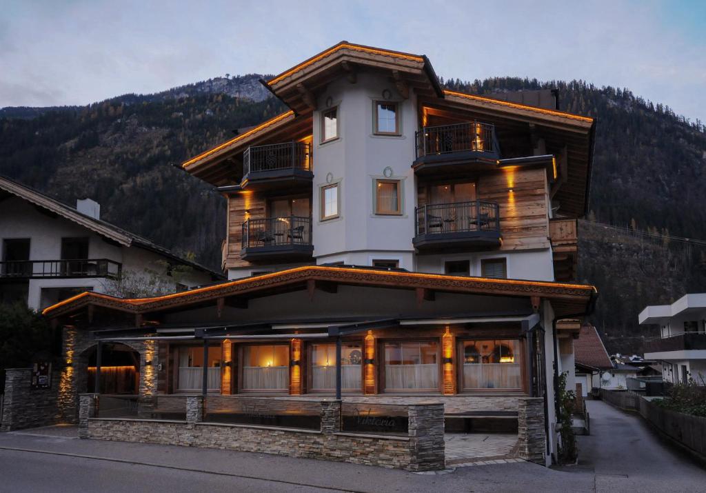 a large white building with a mountain in the background at Hotel Viktoria & Landhaus Joggl in Mayrhofen