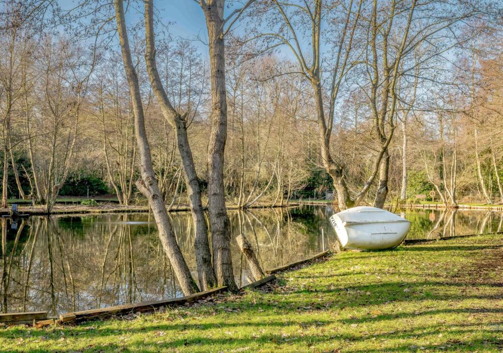 a boat sitting on the grass next to a body of water at The Roost - Glen Farm in Thurgarton