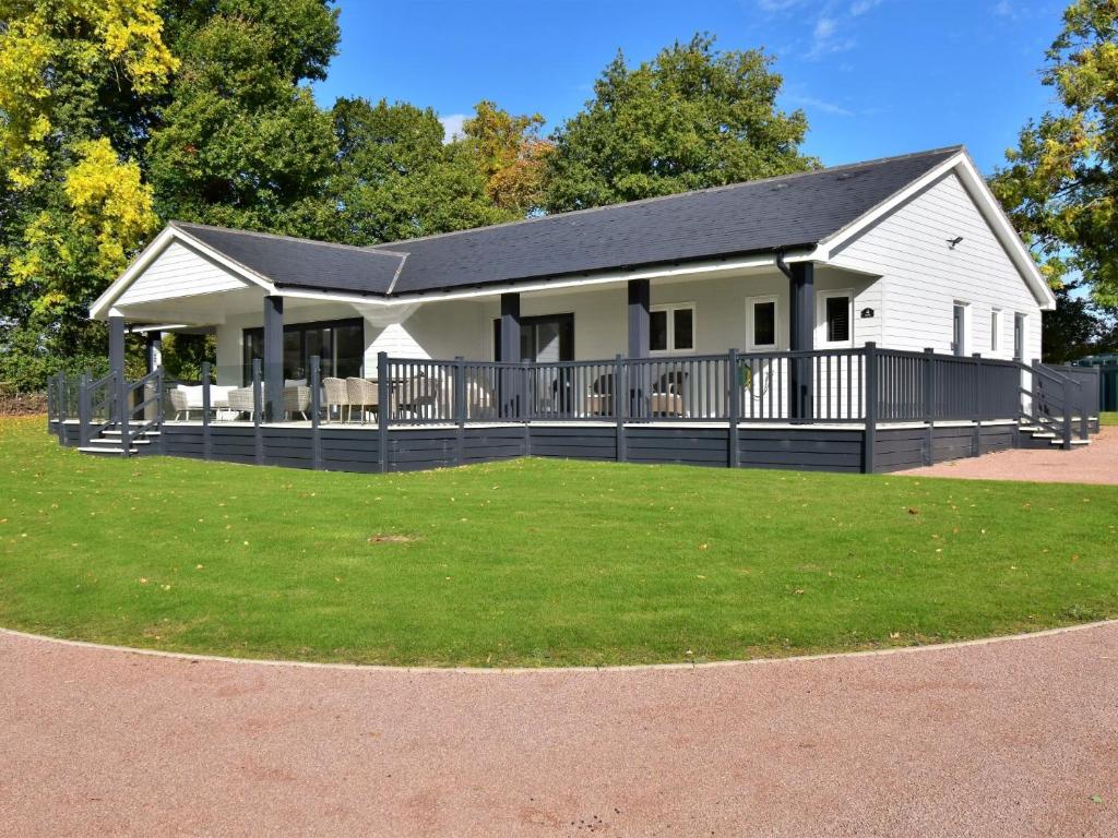 ein weißes Haus mit einem schwarzen Dach und einem Hof in der Unterkunft 4 Bed in Oswestry 75175 in Kinnerley