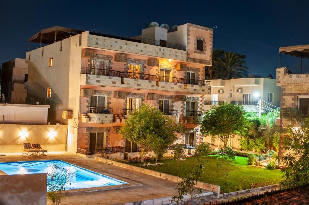 un edificio de apartamentos con piscina por la noche en New Memnon Hotel en Luxor