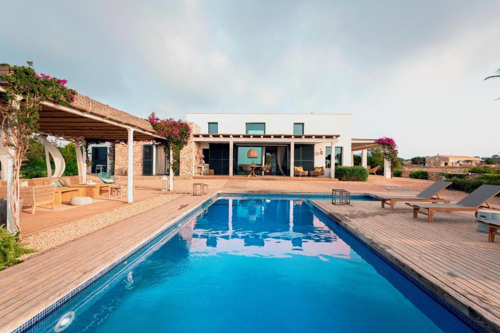 een zwembad met een houten terras en een huis bij Somnis in La Mola