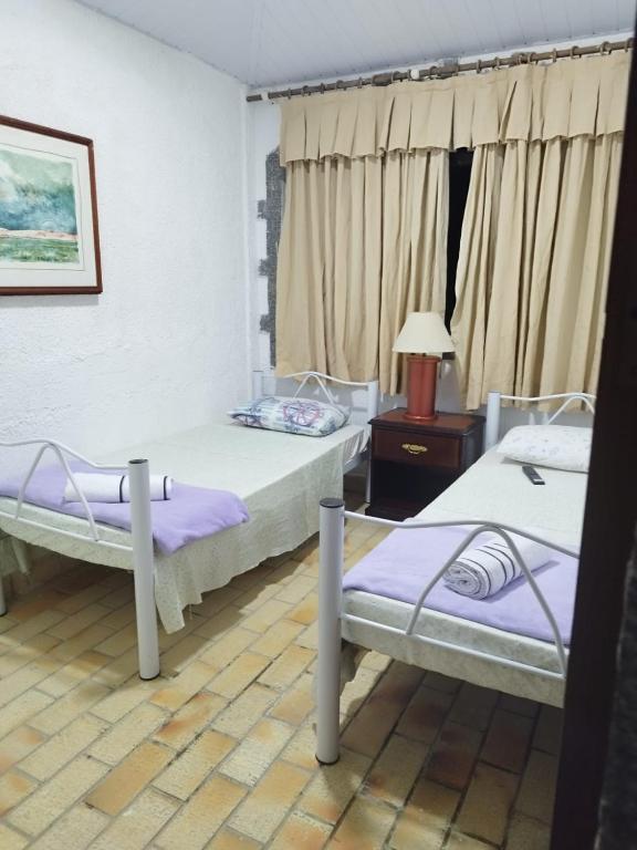 een kamer met 2 bedden en een tafel met een lamp bij Trairão do Encantado in Guararema