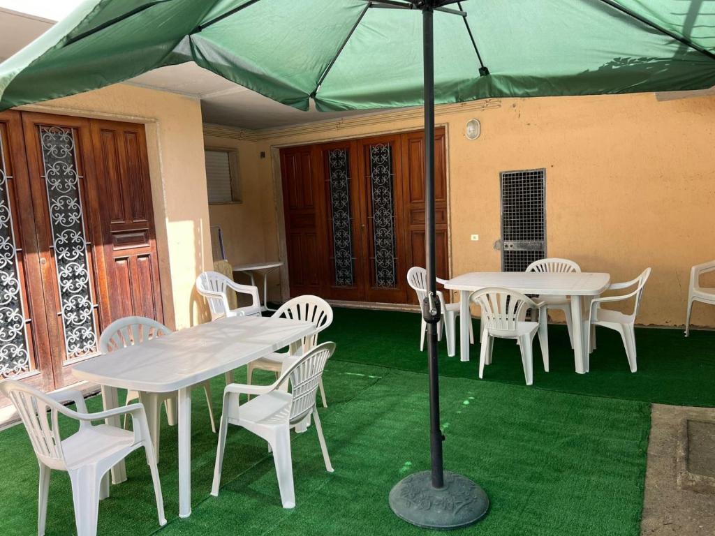 eine Gruppe von Tischen und Stühlen unter einem grünen Schirm in der Unterkunft Appartamento GIANNUTRI in Follonica