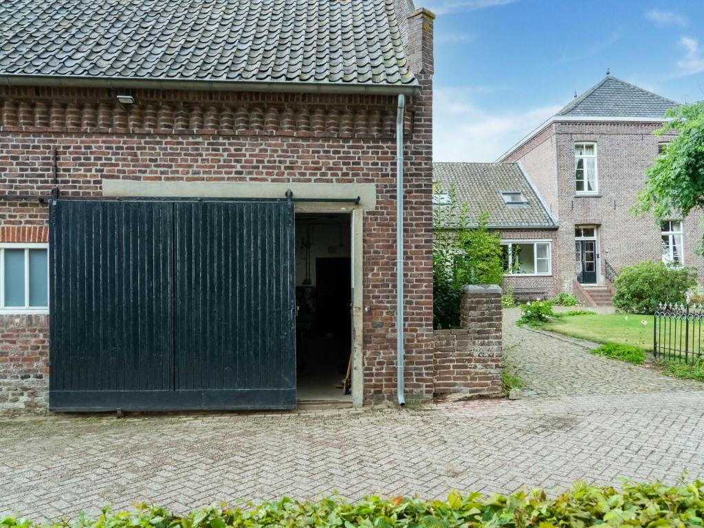 um edifício de tijolos com uma porta de garagem preta em Spacious Mansion in Swolgen with Garden em Swolgen
