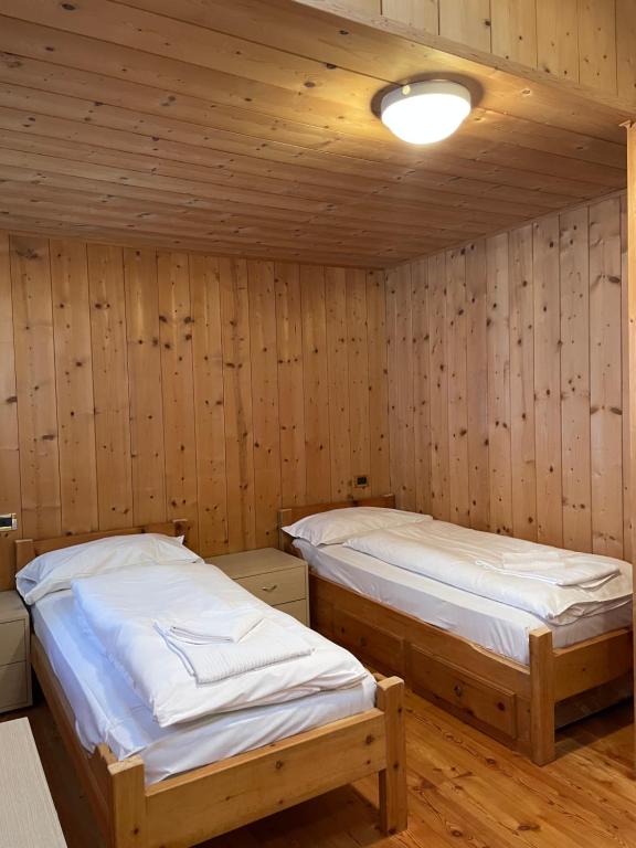 two beds in a room with wooden walls at Cèsa Niki in Canazei