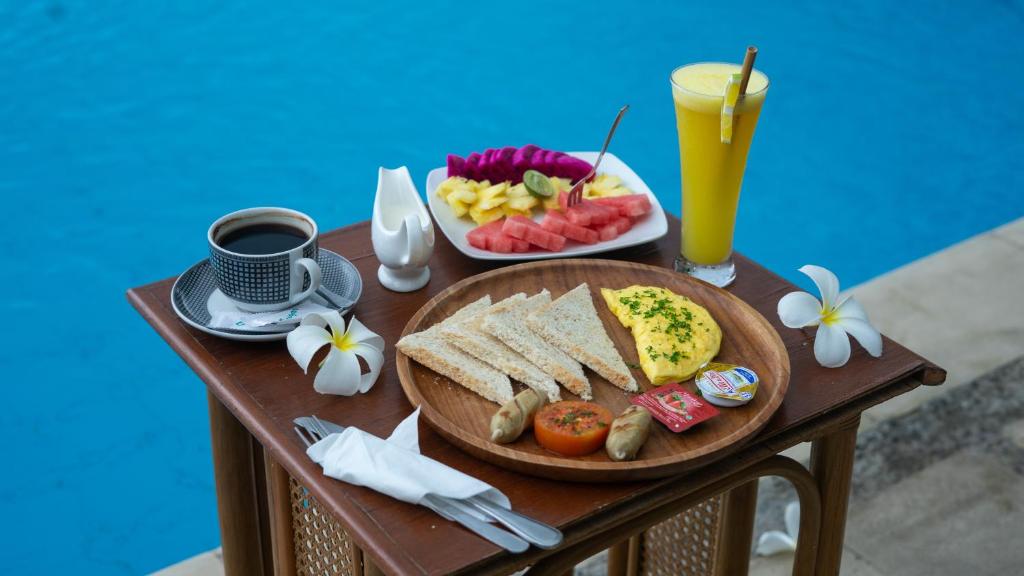 a table with a plate of breakfast food and a drink at Anda Amed Villas & Spa in Amed
