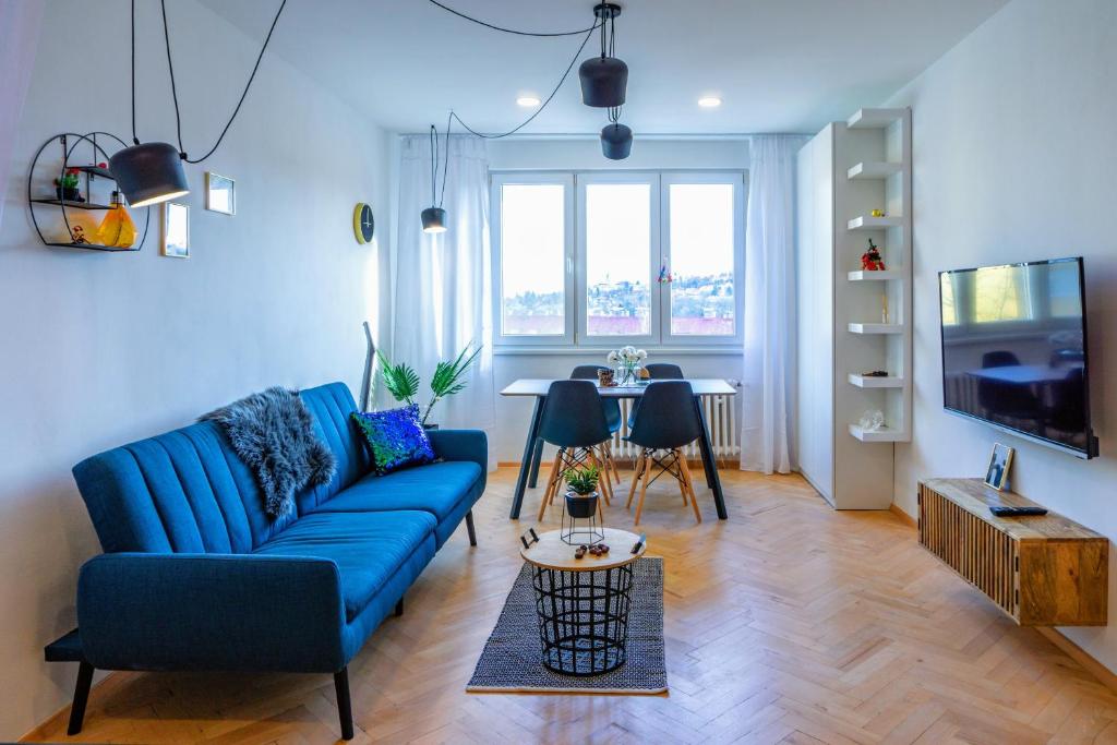 a living room with a blue couch and a table at Jana's WoW apt, 2BR, Metro next door, near the airport in Prague