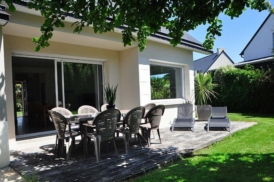 een terras met een tafel en stoelen in een tuin bij Maison Roche Blanche in Port Blanc