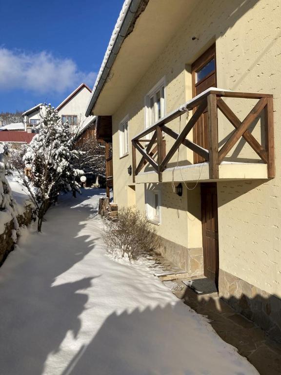 a snow covered sidewalk next to a building with a wooden balcony at Chalupa Barbolica in Vernár