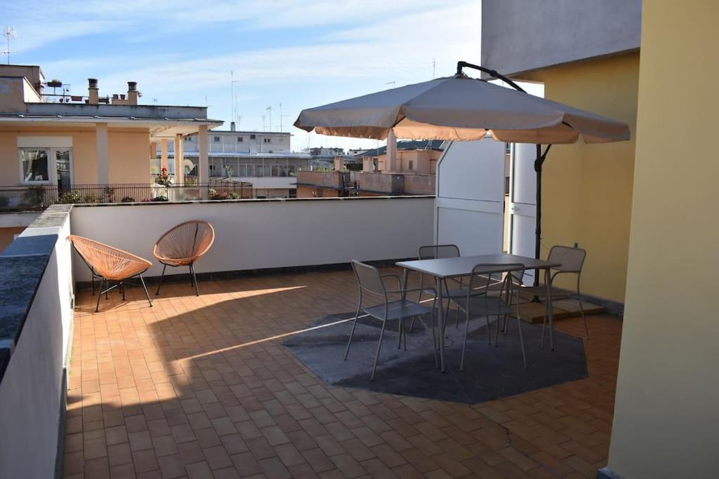 a patio with a table and chairs and an umbrella at Attic with terrace on Conca d'oro in Rome