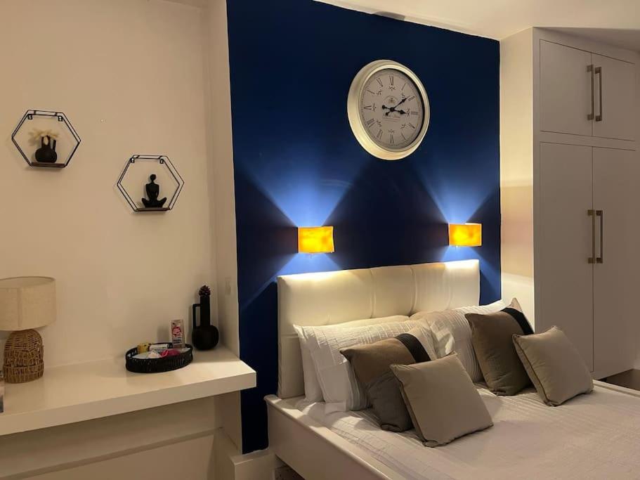 um quarto com uma parede azul com um relógio por cima da cama em Modern studio in Barbican EC1 - blue - F4 em Londres