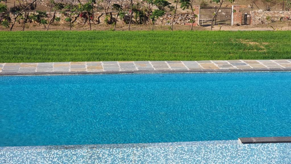 - une piscine d'eau bleue dans la cour dans l'établissement The Aawargarh Retreat, à Jharol