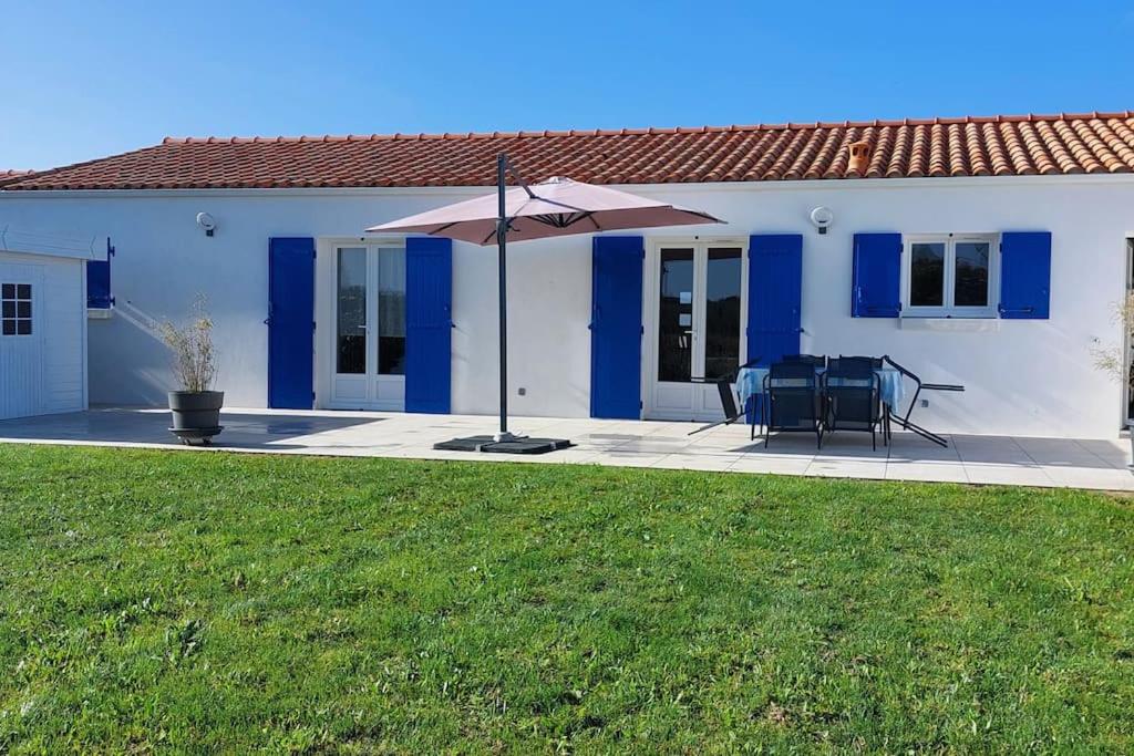 a blue and white house with a table and an umbrella at Maison neuve 6/8p à La Cotinière in La Cotinière